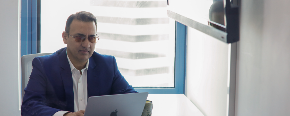 a man in a suit and tie sitting at a desk with a laptop